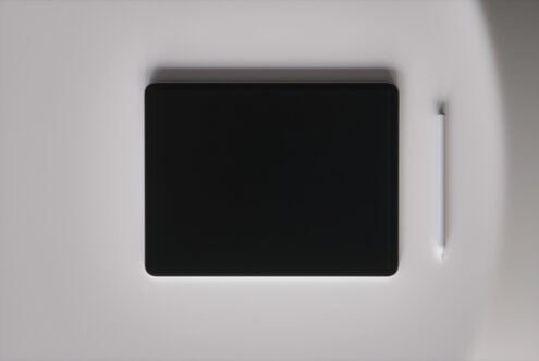 Tablet with stylus on neutral gray surface, overhead shot