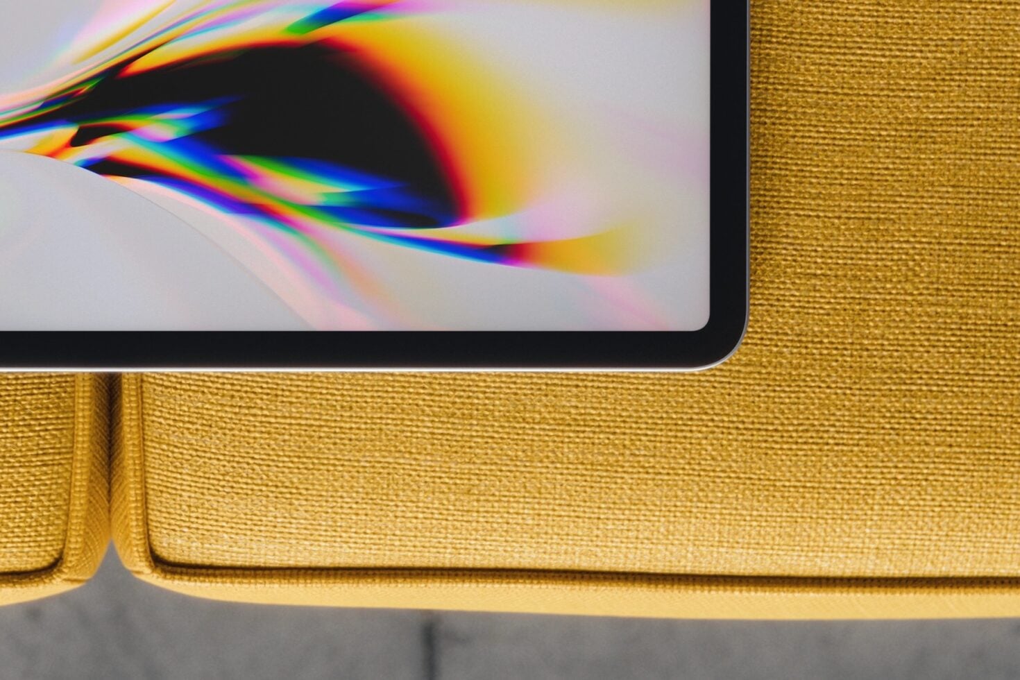 Laptop displaying vibrant rainbow light refraction on mustard yellow fabric couch