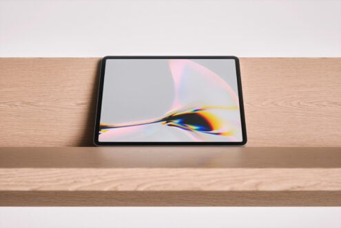 Tablet mockup on wooden desk with colorful light refraction artwork on screen