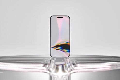 iPhone 14 Pro mockup with rainbow prism display, sitting on reflective glass surface