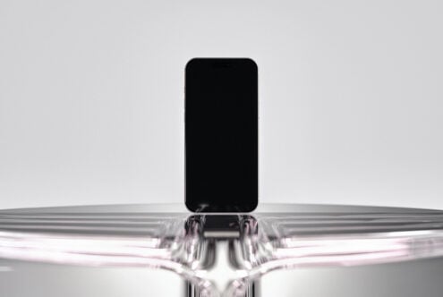 Black iPhone mockup emerging from liquid metal splash on gray backdrop