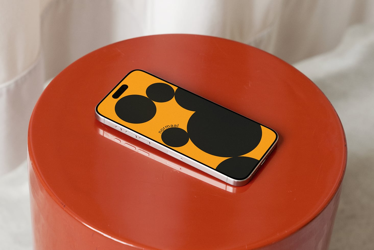 Smartphone mockup with bold yellow case displaying black circular camera cutouts, sitting on a rust-red cylindrical surface