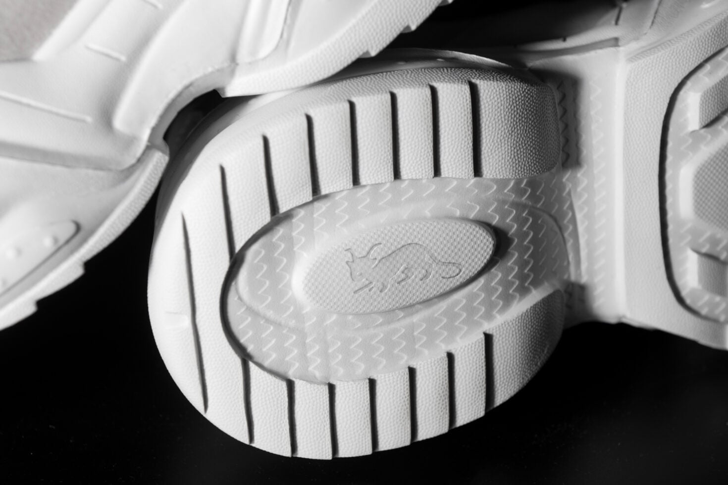 Overhead shot of white sneaker sole with deep tread pattern, textured grip details visible