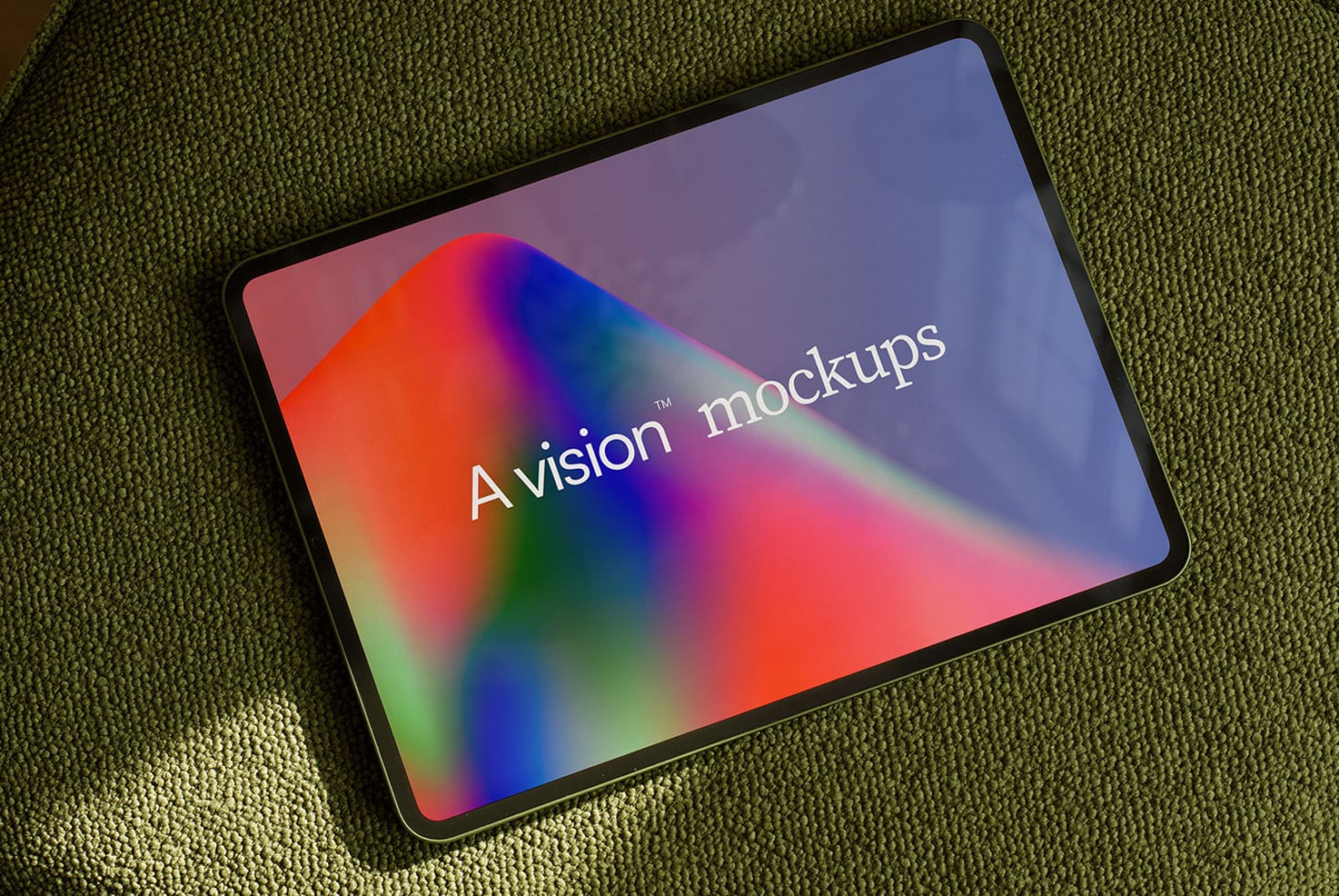 iPad on olive fabric showing colorful gradient display with "vision mockups" text