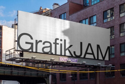 Large outdoor billboard mockup showing "Grafik JAM" text on white surface with brick buildings behind