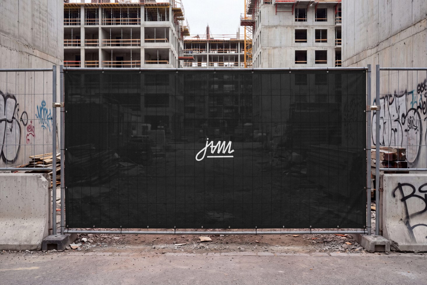 Black construction site gate with white cursive logo, concrete buildings in background