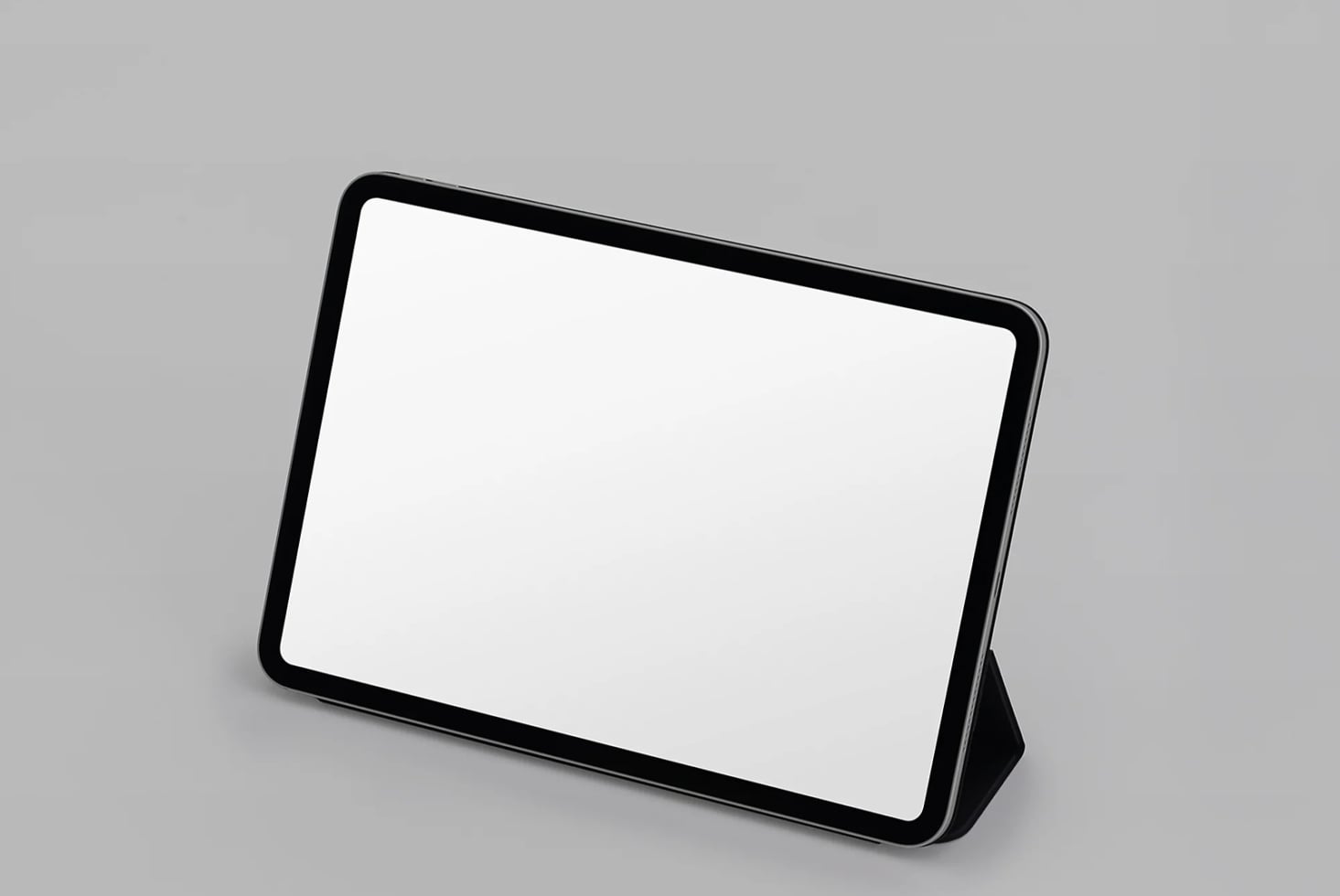 Black tablet with stand on gray surface, blank screen ready for your design