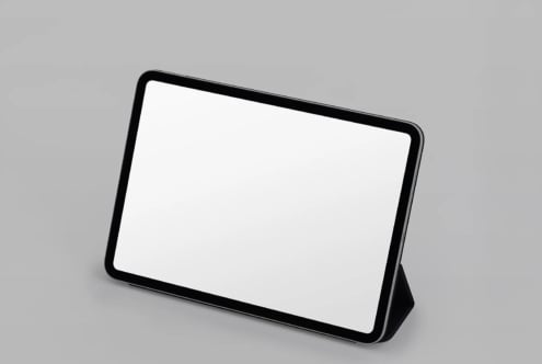Black tablet with stand on gray surface, blank screen ready for your design