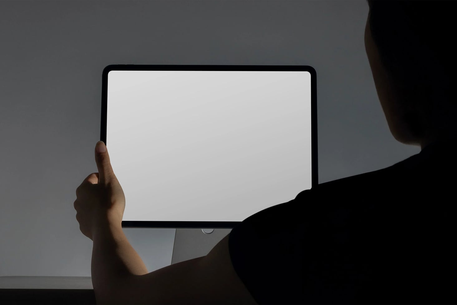 Person holding tablet with blank screen, shoulder visible in frame