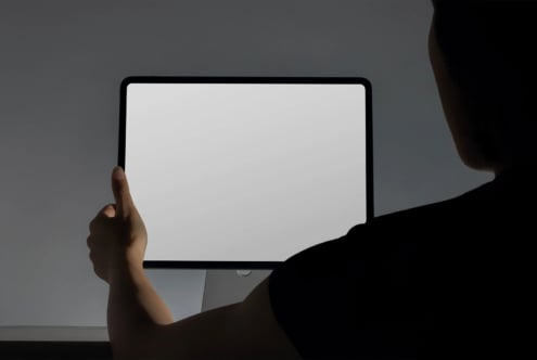 Person holding tablet with blank screen, shoulder visible in frame