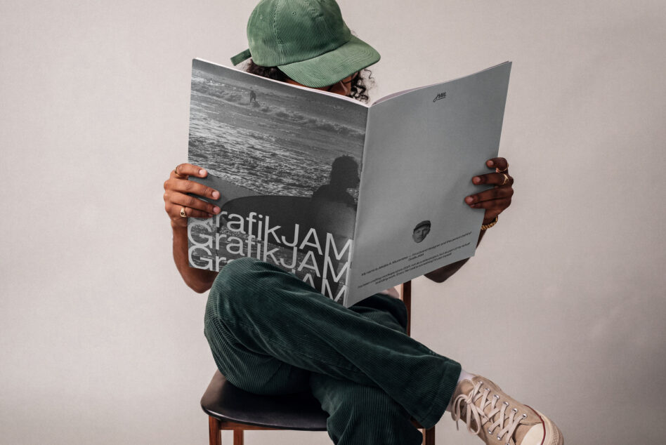 Person sitting in green cap reading open magazine mockup with beach photo on cover