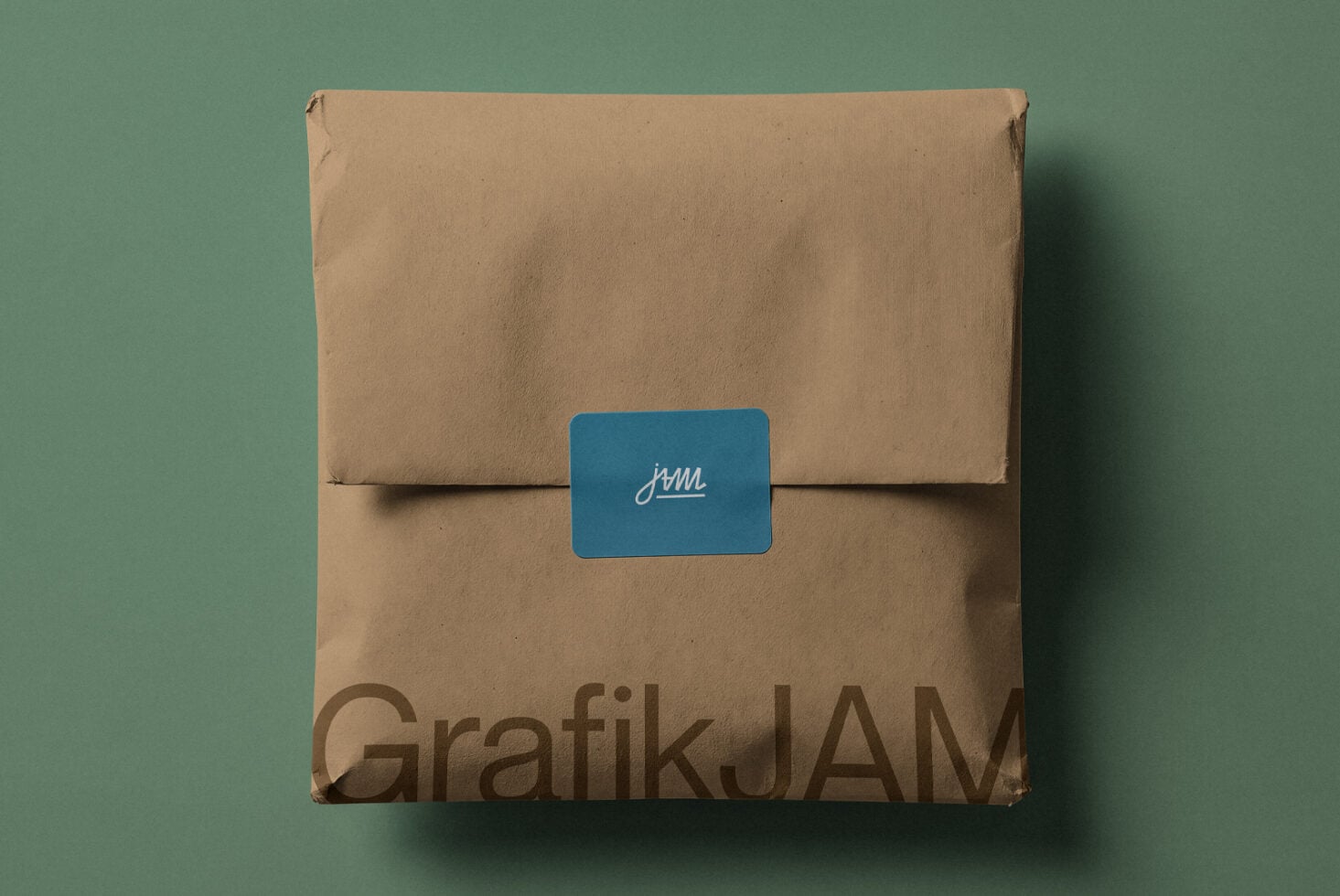 Kraft cardboard box with blue label showing cursive jam logo on sage green background