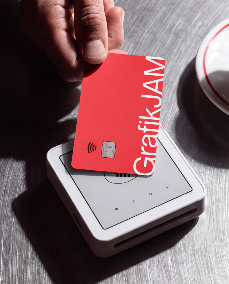 Hand holding bright red credit card over payment terminal mockup