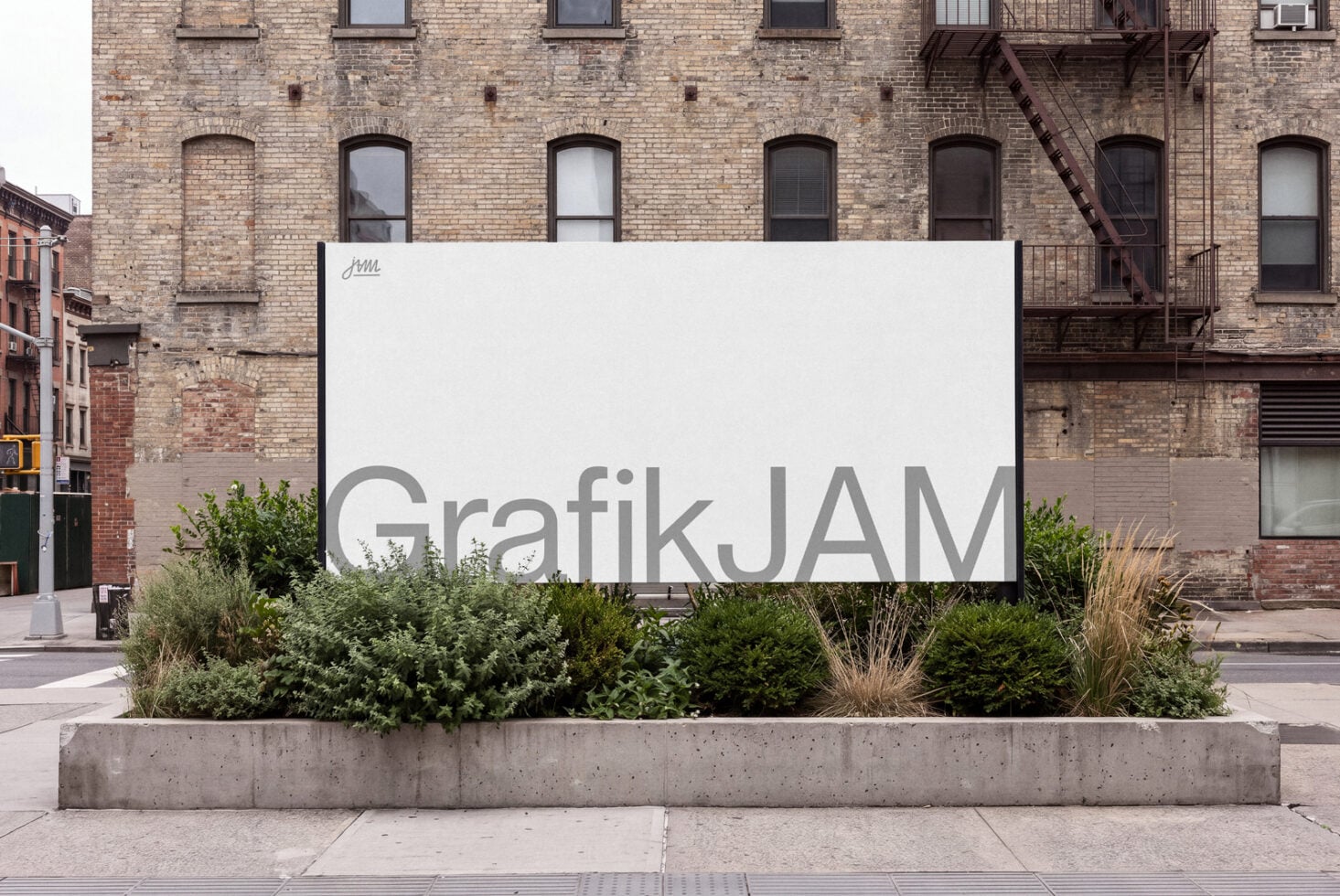Large white billboard mockup on urban street with brick buildings, concrete planter box with greenery below