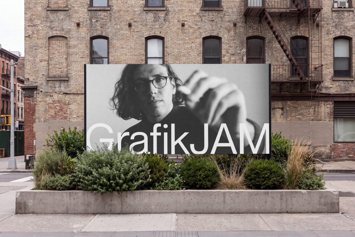 Large outdoor billboard mockup mounted on concrete planter with brick building backdrop