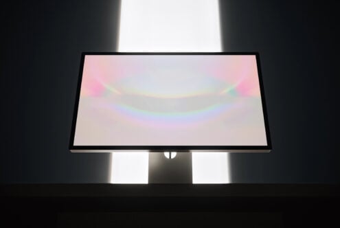Desktop monitor mockup with soft pastel gradient on screen, dramatic studio lighting