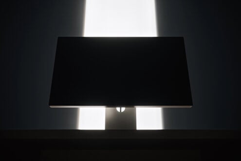 Monitor mockup with black screen on stand, backlit by bright window