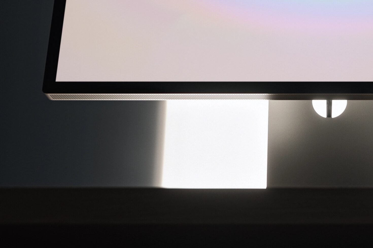 Minimal desk setup with monitor displaying soft gradient, smartphone mockup, lamp casting warm glow