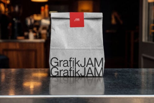 Kraft paper bag with red band label on dark cafe counter, warm bokeh background