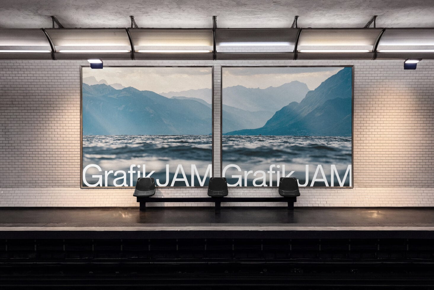 Two large framed landscape photos of mountains meeting water displayed on subway station wall above bench