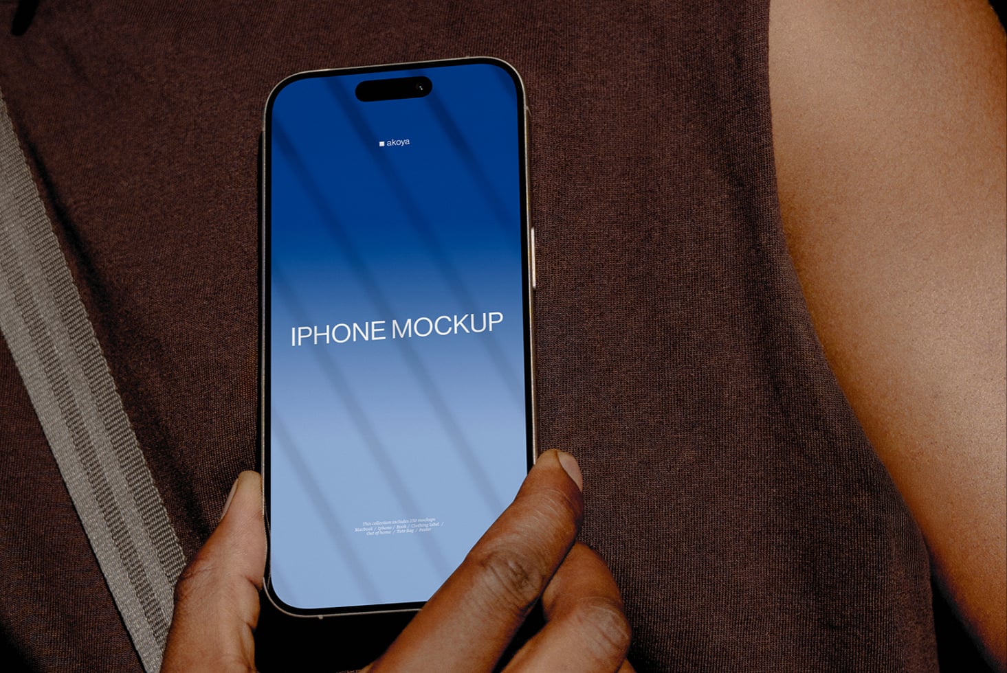 Hand holding iPhone with blue gradient screen displaying mockup text on fabric background