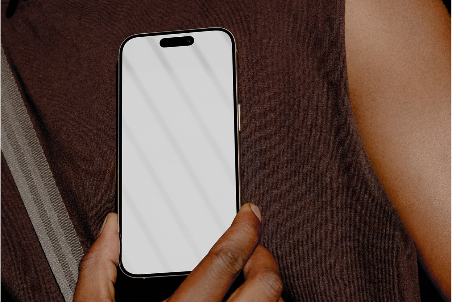iPhone mockup held in hand against brown fabric background with natural lighting
