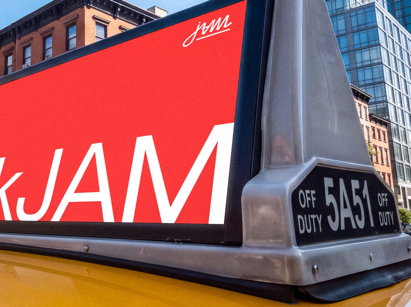 Bright red taxi roof sign with white lettering against NYC street backdrop