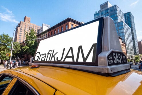 Oversized taxi roof sign mockup with GrafikJAM branding on yellow cab in NYC street scene