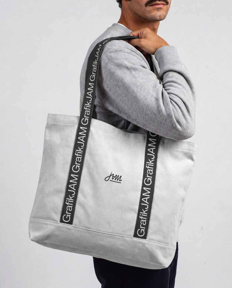 Guy wearing gray hoodie carrying white canvas tote with branded black straps