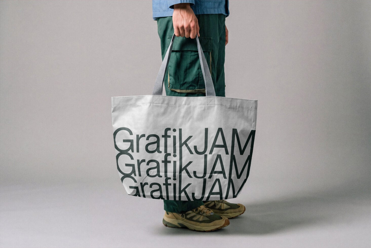 Person holding white canvas tote bag with repeated text design mockup