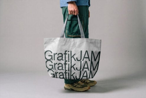 Person holding white canvas tote bag with repeated text design mockup