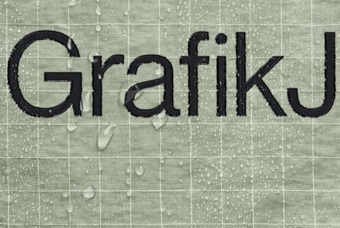 Bold black serif letters spelling Grateful on textured green tile background with grid pattern