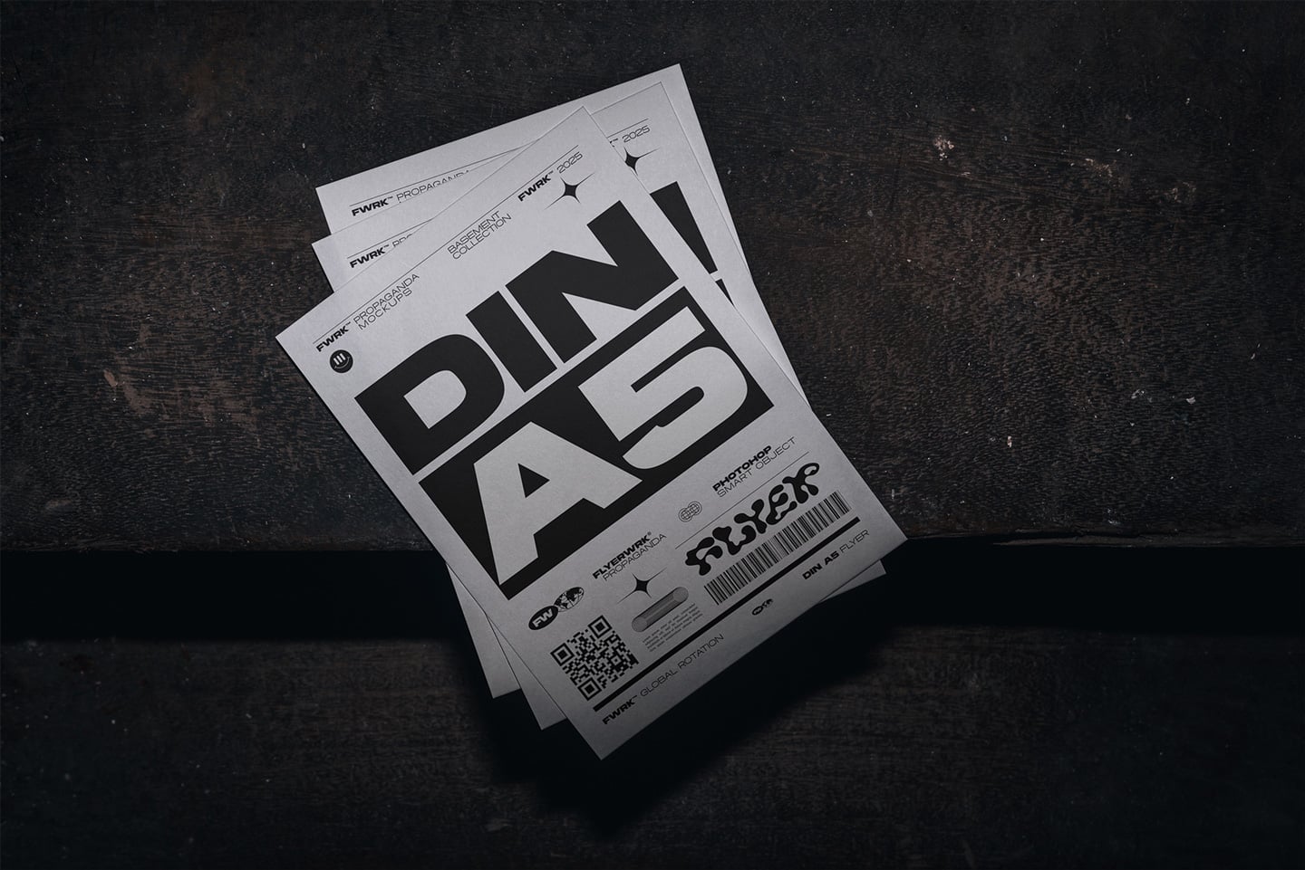 Stacked flyers with bold black typography on white paper, shot overhead on dark textured background