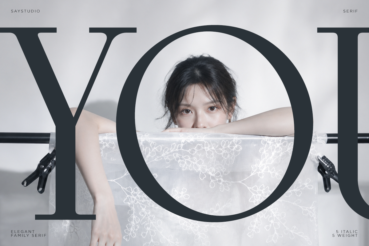 Woman peeking through large serif letterforms, minimal aesthetic with delicate lace fabric overlay