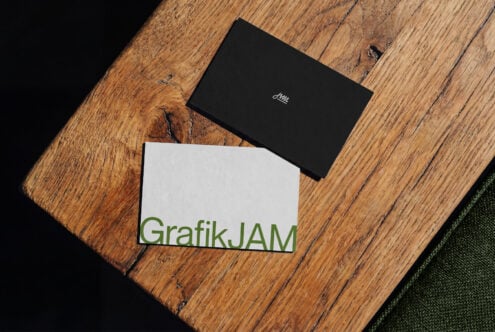 Black laptop with white script logo on distressed wood beside white business card with green text