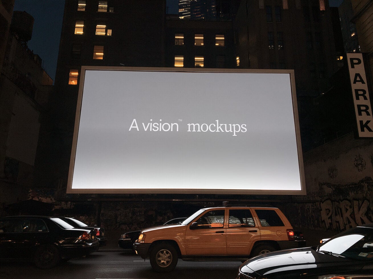 Nighttime urban billboard mockup with lit building windows, parked cars below, showing blank screen ready for design