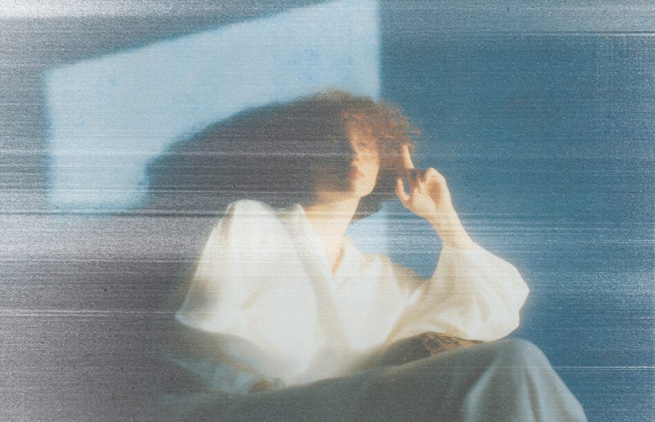 Person in white shirt holding camera with dreamy double exposure effect, cool teal color grading