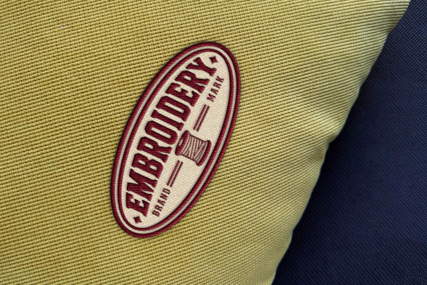 Embroidered logo patch on yellow fabric with navy contrast showing stitched detail