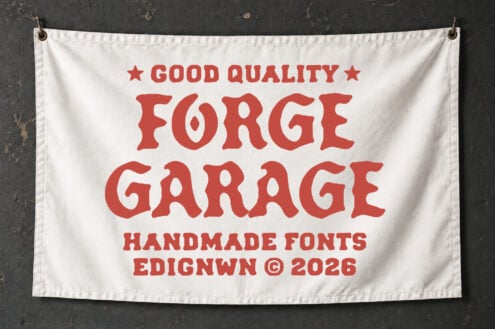 Cream banner with red vintage lettering reading "Good Quality Forge Garage" hung on dark textured wall