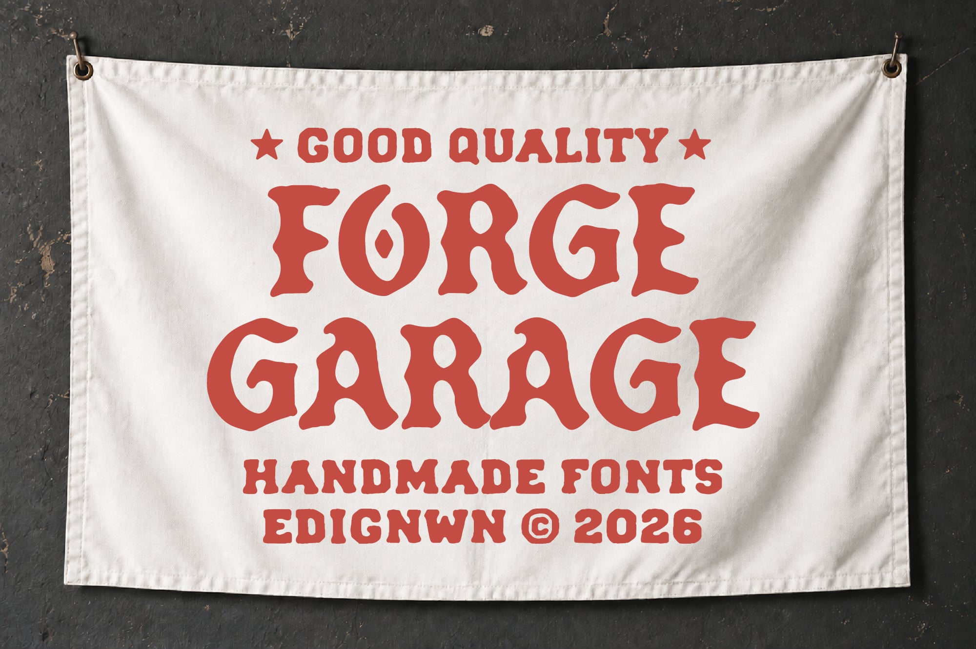 Cream banner with red vintage lettering reading "Good Quality Forge Garage" hung on dark textured wall
