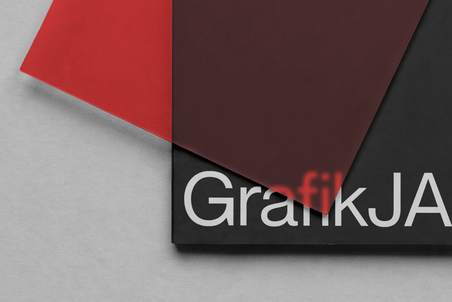 Overlapping colored papers with black label showing GraffikJA branding on gray surface