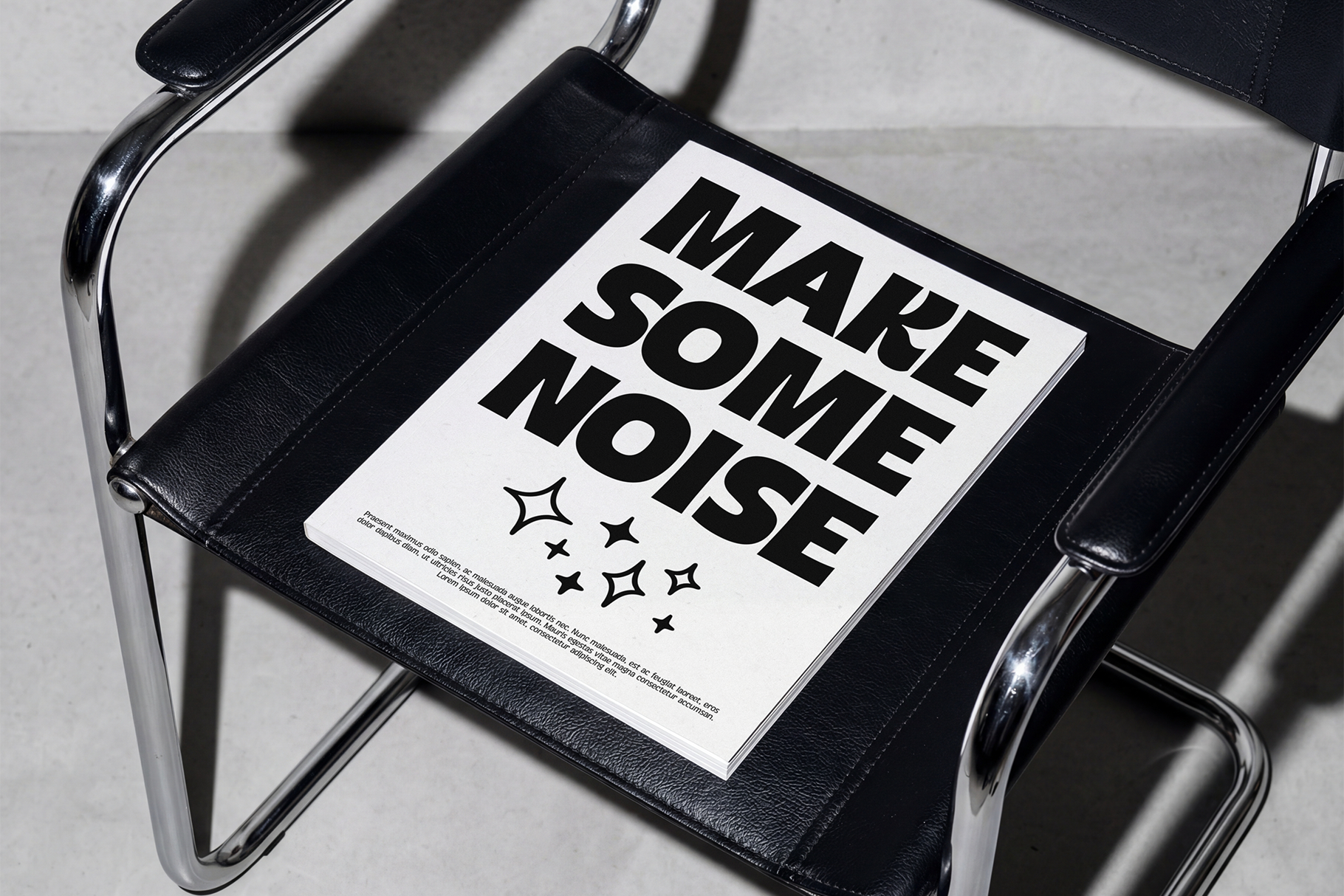 Poster mockup on black leather chair showing bold typography with "Make Some Noise" text in stark black against white paper