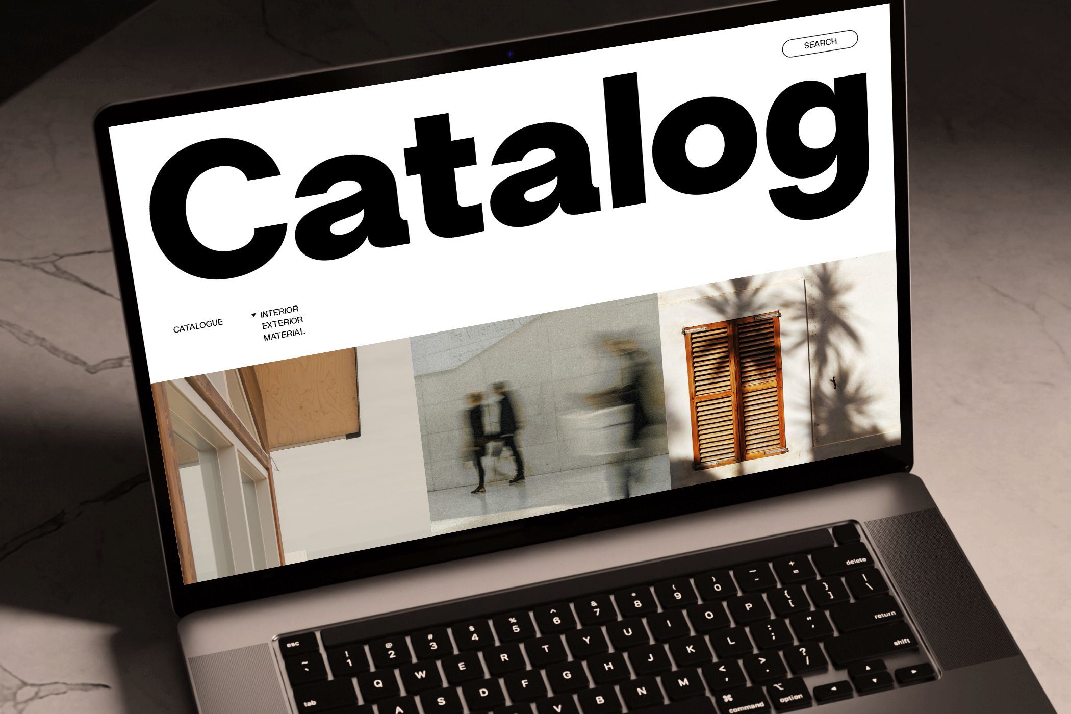 Laptop displaying minimalist catalog website with bold typography, interior exterior material imagery, search bar