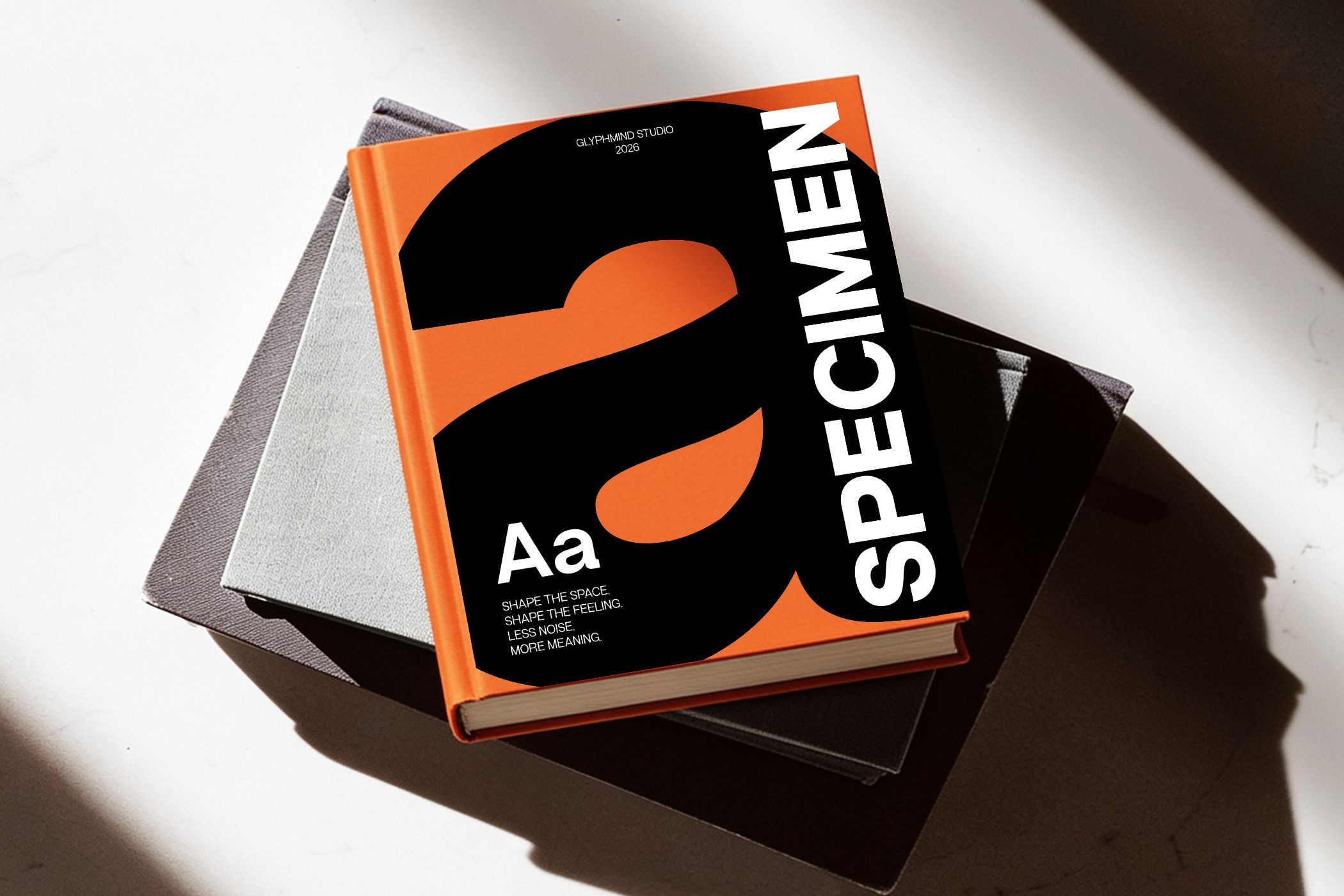 Stacked design books with bold orange cover featuring geometric shapes with "Specimen" text