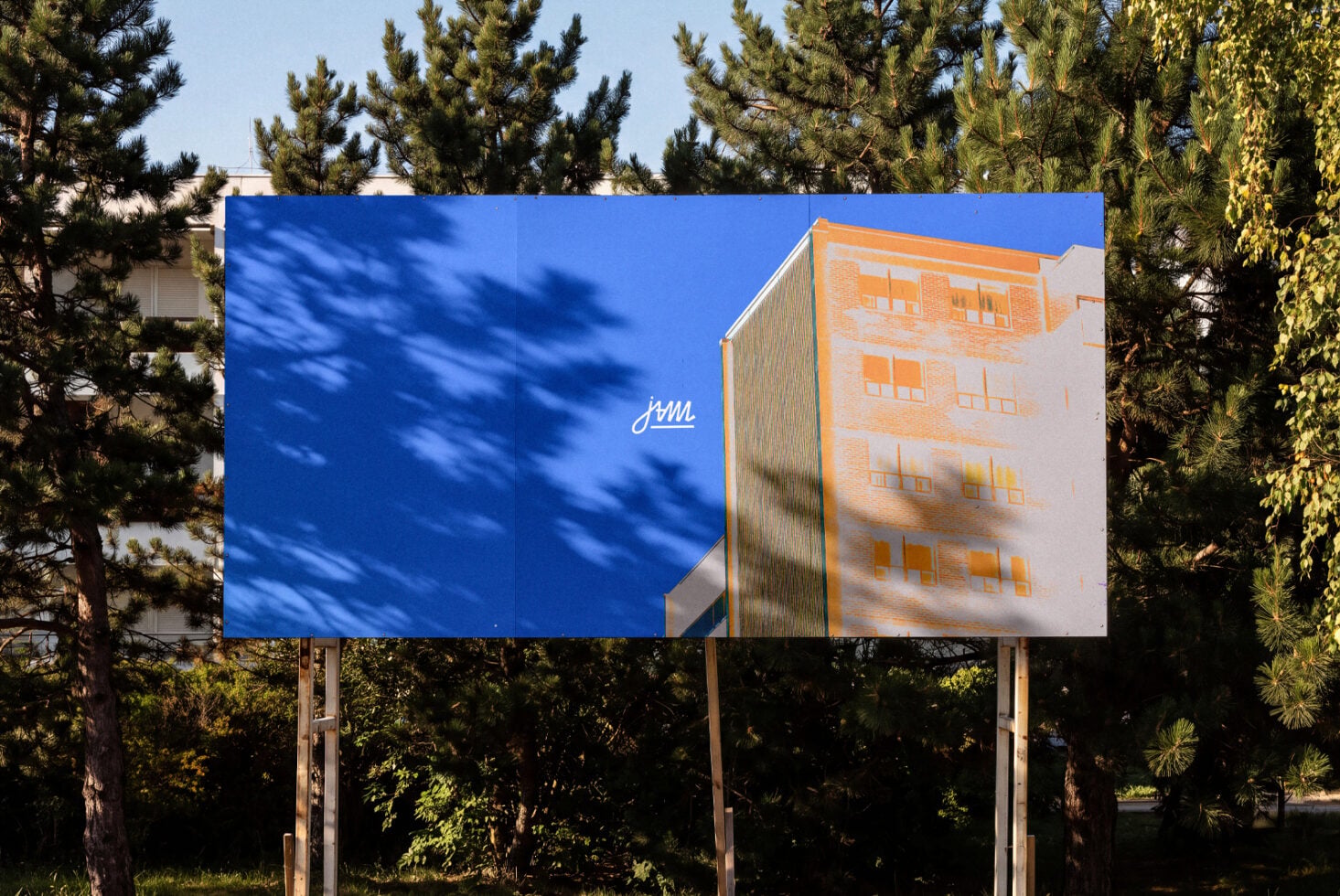 Outdoor billboard mockup with split blue sky plus orange brick building photo, surrounded by pine trees