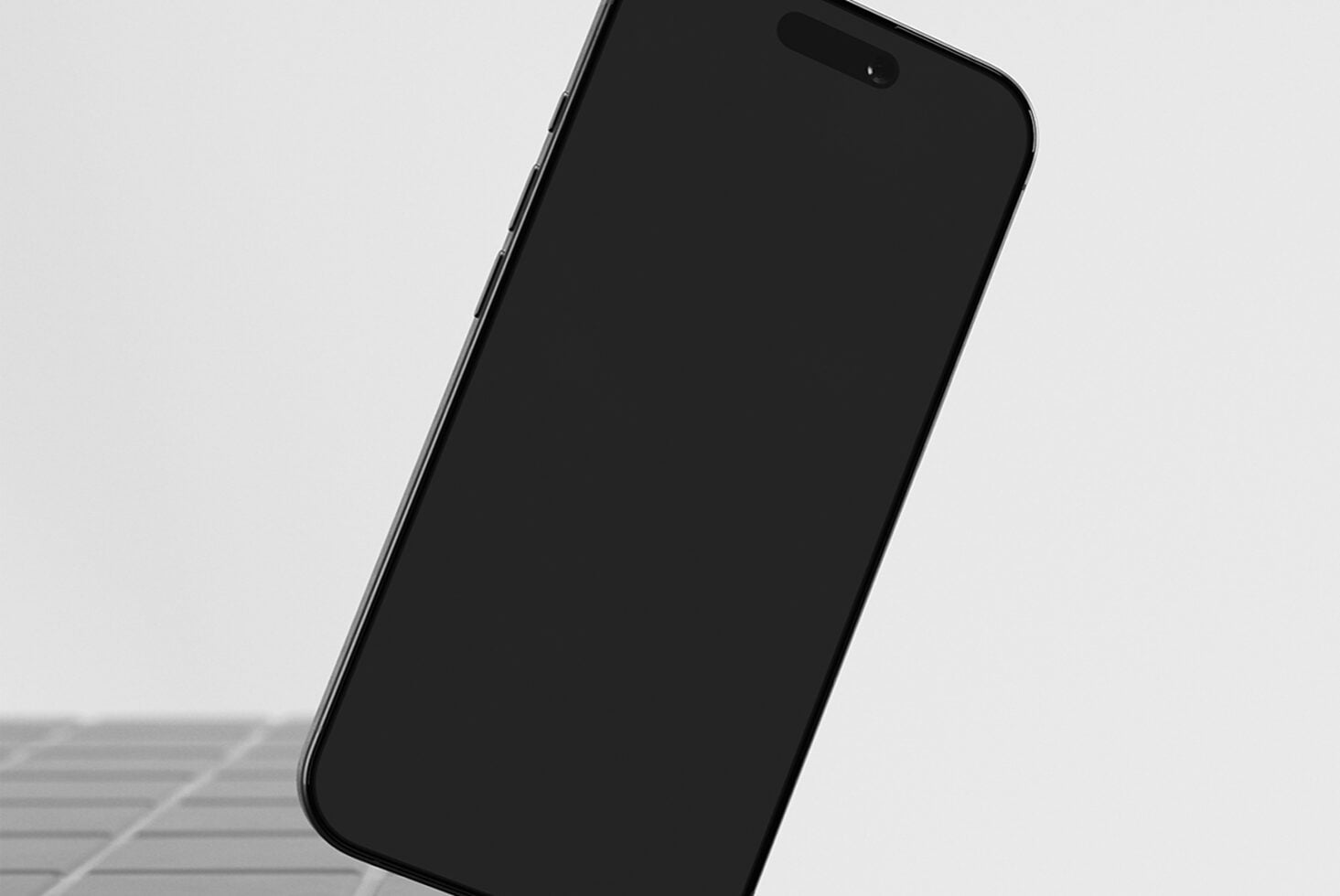 Black iPhone tilted at an angle on a light background with minimal shadow