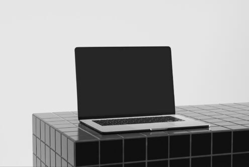 Silver laptop on geometric grid platform with minimal background