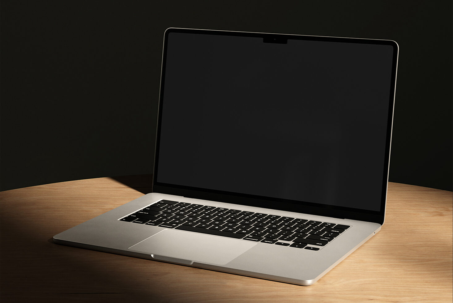 Silver MacBook Pro sitting on wooden desk with dark background