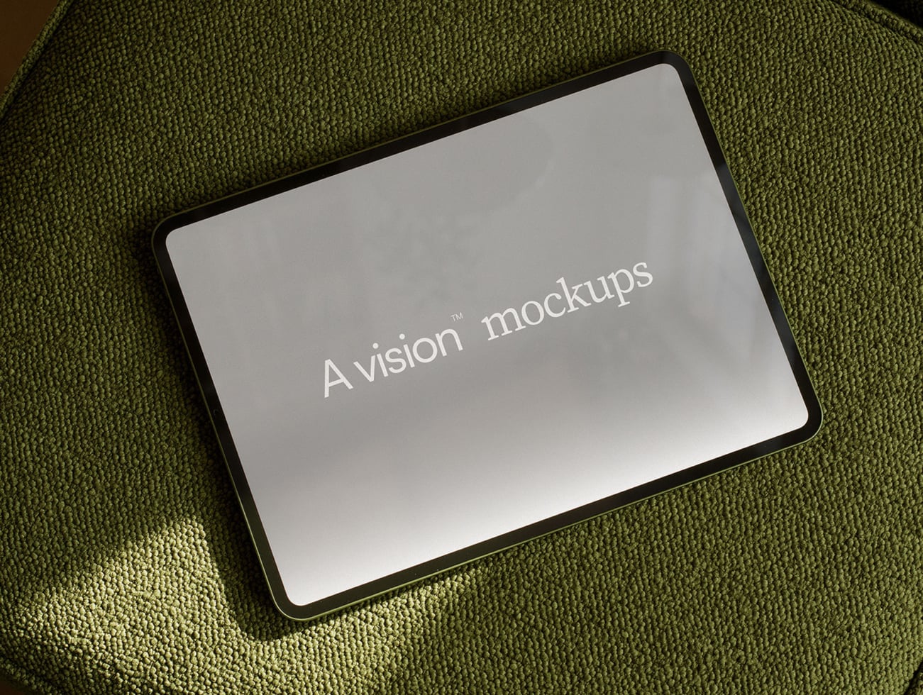 Tablet with rounded black frame on olive green fabric, displaying centered white text on gray screen