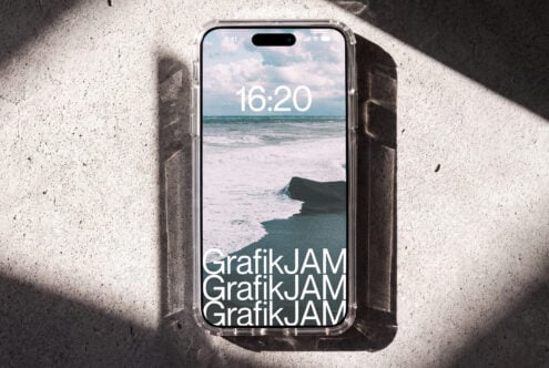 iPhone 14 Pro mockup showing beach lockscreen with GrafikJAM branding on concrete